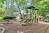 Charming playground nestled in a lush green area with nearby cozy homes, ideal for family-friendly living.