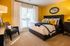 Chic bedroom with vibrant yellow accents, plush bedding, and a cozy armchair bathed in natural light.
