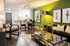 Modern open-concept living room with stylish decor, green accent wall, and cozy seating next to a sleek kitchen area.