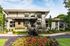 Modern leasing office with sleek architecture, surrounded by vibrant landscaped gardens and lush greenery.