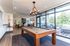 Luxurious apartment lounge featuring a modern pool table, elegant seating, and floor-to-ceiling windows with lush views.