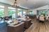 Inviting open-concept living room with stylish leather chairs, modern sofa, and expansive windows offering scenic views, adjacent to a chic dining area and contemporary kitchen.