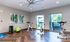 Bright and modern apartment gym with spin bikes, free weights, and stylish wooden flooring, complemented by abstract artwork and large windows offering lush greenery views.