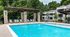 Inviting outdoor pool area with elegant stone pergola and stylish loungers surrounded by lush greenery, perfect for relaxation.