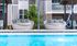 Luxurious outdoor lounge with stylish round wicker seating overlooking a sparkling pool, perfect for relaxation and enjoying sunny days.