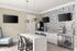 Modern kitchen space with sleek white countertops, mosaic tile backsplash, and stylish pendant lighting.