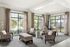 Stylishly furnished living room with large windows, elegant armchairs, and a modern dining area.