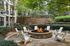 Charming outdoor fire pit surrounded by Adirondack chairs amidst lush greenery.