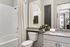 Bright, modern bathroom with a bathtub, sleek granite countertop, and stylish fixtures.