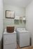 Inviting laundry room featuring a washer, dryer, wicker basket, and neatly arranged shelves with jars and towels.