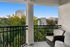 Inviting balcony with wicker chair overlooking a vibrant cityscape and lush greenery.