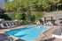 Inviting outdoor pool area with modern lounge chairs, surrounded by lush greenery and stone walls, perfect for relaxation.