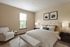 Sophisticated bedroom with a plush queen-sized bed, accent chair, and tasteful decor.