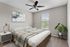 Cozy bedroom with a stylish bed, modern artwork, and a lush potted plant near the window.