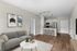 Stylish living room with a modern gray sofa, chic artwork, and an open kitchen design.