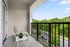 Modern apartment balcony with a comfortable chair and table overlooking lush greenery.