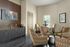 Chic living room with four stylish patterned chairs, a modern art piece, and elegant wooden cabinetry.