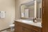 Modern bathroom with wooden cabinets, large mirror, and elegant countertop.