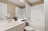 Modern bathroom design featuring elegant white fixtures, a spacious bathtub, and a large vanity mirror with stylish decor accents.