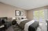 Bright and inviting bedroom with modern decor, plush bedding, and a private balcony showcasing a scenic view.