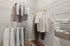 Spacious walk-in closet with elegant shelving and ample hanging space, showcasing neatly organized clothing and luxurious folded towels.