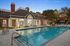 Elegant poolside retreat at a luxury apartment complex, featuring a beautifully lit swimming pool and stylish clubhouse with classic architecture.