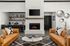 Elegant living room with a cozy fireplace, stylish orange sofas, and a modern marble coffee table, perfect for relaxation and entertaining.