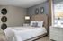 Elegant bedroom with plush upholstered bed, chic wall art, and stylish bedside tables illuminated by soft lamps.