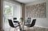 Contemporary dining area with glass table, modern chairs, and floor-to-ceiling windows offering garden views.