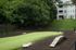 Serene apartment dog park with lush green turf, surrounded by trees and modern building.