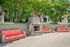 Charming outdoor space with stylish stone fireplace, vibrant orange seating, and lush greenery, perfect for relaxation and social gatherings.
