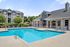 Inviting apartment complex featuring a sparkling outdoor swimming pool, modern lounge chairs, and charming architecture set against lush greenery.