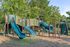 Inviting playground with vibrant slides, climbing structures, and a tunnel slide surrounded by lush greenery.