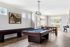 Bright recreational room featuring a pool table, shuffleboard, and stylish decor with modern artwork and large windows.