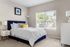 Bright and inviting bedroom with a plush navy bed, elegant decor, and large window with scenic view.