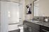 Elegant bathroom featuring sleek granite countertops, a modern vanity, and a stylish bathtub with white subway tiles.