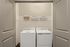 Modern laundry area featuring a washer and dryer with overhead shelving for organization.