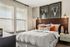 Bright bedroom with stylish decor, featuring a comfortable bed, cozy pillows, and modern wall art.