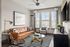 Stylish living room featuring a tan leather sofa, elegant glass coffee table, and modern decor.