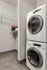 Modern laundry area with a stacked washer and dryer, next to a spacious storage shelf.