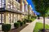 Charming exterior view of a modern apartment complex with well-maintained landscaping and bright evening lighting.