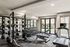 Modern gym with weightlifting equipment, treadmill, and outdoor view through large windows.