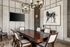 Stylish dining room with a large wooden table, modern chandelier, and art piece depicting a horse on the wall.