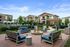 Inviting outdoor patio area with stylish seating and fire pit, surrounded by modern apartment buildings.