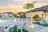 Charming outdoor pool area with palm trees and lounge seating against a sunset backdrop.