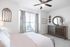 Bright and welcoming bedroom with a large window, stylish dresser, and decorative elements.