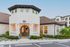 Stylish entrance of a modern apartment complex featuring a round doorway, lantern lights, and beautifully landscaped surroundings.