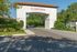 Elegant entrance archway at Cortona, surrounded by lush greenery under a clear blue sky.
