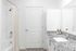 Bright and modern bathroom with granite countertop and white cabinetry.