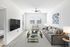 Bright and modern living room with a sleek sofa, glass coffee table, and wall-mounted TV.